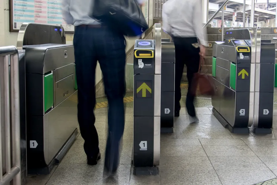 People entering modern fare gates in subway station.